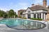 Elegant apartment complex featuring a luxurious poolside area with seating and lush greenery, perfect for relaxation and leisure.
