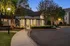 Charming evening view of a beautifully landscaped clubhouse surrounded by lush greenery and elegant lighting.