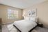 Bright and inviting bedroom with large window, elegant decor, and plush carpet, ideal for relaxation and comfort.