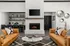 Elegant living room with a cozy fireplace, stylish orange sofas, and a modern marble coffee table, perfect for relaxation and entertaining.