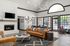 Elegant living room with modern decor, featuring a plush leather sofa, stylish chandelier, and large windows offering abundant natural light.
