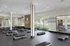 Modern wellness center featuring a spacious exercise area with large mirrors, vibrant natural light, and sleek fitness equipment.