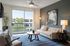 Bright and modern living room with stylish furniture, large artwork, and floor-to-ceiling windows overlooking a lush view.