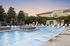 Luxurious outdoor pool area with modern sun loungers and lush landscaping, perfect for relaxation at sunset.