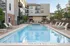 Inviting community swimming pool area with lounge chairs and umbrellas, set against a modern apartment building backdrop.