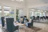 Elegant community lounge with stylish blue armchairs, a geometric patterned rug, and large windows offering abundant natural light.