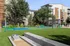 Modern apartment complex with lush greenery, tennis court, and seating areas, ideal for outdoor activities and relaxation.