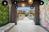 Chic apartment entry with artistic mural leading to a luxurious pool area featuring stylish loungers and vibrant greenery.