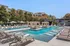 Luxurious apartment pool area with elegant lounge chairs, stylish cabanas, and crystal-clear water, surrounded by lush greenery and modern architecture.