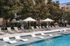 Luxurious outdoor pool area with adjustable loungers, elegant umbrellas, and crystal-clear water, surrounded by tranquil greenery.