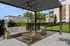 Modern outdoor patio with stylish wicker furniture set under a sleek pergola, surrounded by lush greenery and contemporary architecture.