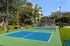 Vibrant outdoor tennis court surrounded by lush greenery, offering a serene and active lifestyle in this luxurious apartment complex.