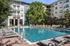 Luxurious apartment complex featuring a sparkling outdoor pool surrounded by stylish lounge chairs and lush greenery.