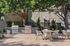 Charming outdoor patio with modern grills and cozy seating area, perfect for entertaining under the shade of lush trees.
