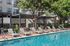 Luxurious apartment poolside with sleek lounge chairs surrounded by lush greenery, perfect for relaxation and leisure.