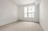 Bright and airy bedroom with large window and plush carpeting, ideal for comfort and relaxation.