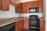 Modern kitchen with elegant wood cabinetry and sleek black appliances, perfect for culinary creativity.
