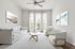 Chic living room with modern furniture, featuring a sleek glass coffee table, plush white sofa, and artistic wall decor, flooded with natural light through elegant tall windows.