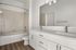Modern bathroom with elegant beige tiles, dual sinks, and chic lighting, offering a luxurious and functional space.