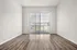 Bright minimalist apartment with elegant wood flooring and large floor-to-ceiling window with vertical blinds, inviting natural light into the open space.