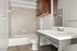 Modern bathroom featuring sleek white fixtures, elegant tile backsplash, and spacious under-sink storage.