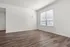 Spacious room with elegant hardwood flooring, large window allowing ample natural light, and freshly painted white walls creating a bright and inviting atmosphere.