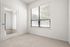Bright, sunlit room featuring a large window with blinds, plush carpet, and a modern glass door with elegant finishes.
