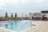 Inviting rooftop pool area featuring chic purple sun loungers, elegant water fountains, and stylish umbrellas, perfect for relaxation and soaking in scenic views.