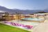 Luxurious rooftop pool area at sunset featuring pink lounge chairs, modern cabanas, and a spacious bar with elegant lighting.