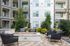 Chic apartment courtyard featuring cozy seating around a modern fire pit, surrounded by lush greenery and stylish balconies.