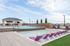 Luxurious rooftop pool area with vibrant purple lounge chairs, elegant cabana, and scenic city views under a clear blue sky.