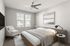Elegant bedroom with modern d&eacute;cor, featuring a cozy bed, stylish chair, and abundant natural light from large windows.