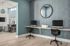 Modern shared workspace with sleek computers, stylish seating, and vibrant blue accent wall in a contemporary apartment.