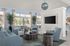 Inviting living room with modern blue armchairs, circular wooden tables, large windows, and elegant decor, offering a bright and stylish space.