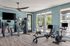 Modern fitness room with state-of-the-art exercise equipment, sunny windows, and sleek flooring.