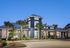 Elegant modern apartment building with contemporary design, large windows, and vibrant landscaping accented by palm trees.