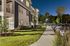 Charming modern apartment exterior with well-lit pathways, surrounded by lush greenery and ample parking at night.