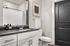Modern bathroom with sleek black countertop, elegant fixtures, and a large mirror, offering style and functionality.