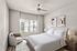 Elegant bedroom with contemporary design, featuring a plush bed, modern armchair, and soft natural lighting through large windows.