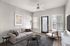 Contemporary living room with chic decor, featuring a cozy beige sofa, stylish black coffee table, and modern ceiling fan, perfect for relaxation.