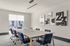 Modern conference room with sleek table, stylish blue chairs, and contemporary artwork on the walls, illuminated by natural light.