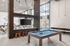 Modern and inviting recreational lounge featuring a stylish billiards table, chic seating, and expansive windows for ample natural light.