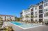 Elegant apartment complex featuring lush palm landscaping and a sparkling outdoor swimming pool, perfect for relaxation and leisure.