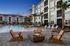 Luxurious apartment complex with a stunning pool, cozy fire pit, and elegant lounge chairs against a sunset backdrop.