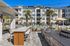 Luxurious apartment complex with a tropical poolside oasis, featuring palm trees, modern outdoor seating, and a sleek barbecue area.