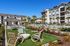 Luxurious apartment complex with a stunning outdoor pool, elegant lounge chairs, and modern landscaping under a clear blue sky.
