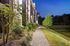 Elegant evening view of a modern apartment complex with beautifully landscaped pathways and serene lakeside scenery.