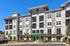 Modern apartment building with stylish architecture featuring large windows, balconies, and a welcoming leasing office surrounded by landscaped greenery.