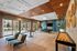 Luxurious recreation room featuring elegant seating, a sleek shuffleboard table, and a stylish ceiling design with views of a vibrant outdoor patio.