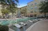 Chic apartment complex featuring a luxurious outdoor pool with modern lounge chairs, surrounded by lush greenery and stylish buildings.